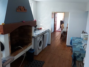 A compact kitchen with a built-in oven, a washing machine, and a dining area with a table set for four.