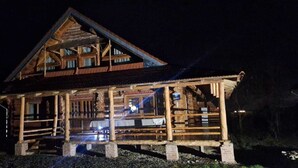 Een vakantiehuisje van hout met een veranda, meerdere ramen en een schoorsteen.