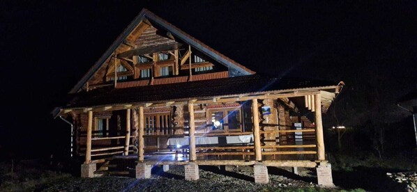 Une cabane en rondins dotée d’une véranda, de nombreuses fenêtres et d’une cheminée.