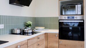 A modern kitchen with a built-in microwave, oven, and a black range hood. - Mid-Century Stay in Val-d'Ajol with Parking and Pets Welcome (Le Val-d'Ajol)