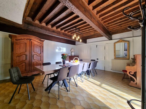 Un comedor con techo de madera, una mesa grande con sillas y un armario con espejo.