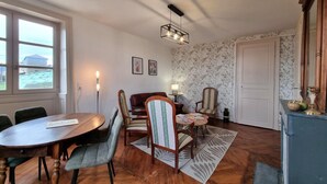 Un comedor con mesa y sillas de madera, alfombra estampada y pared con papel tapiz floral.
