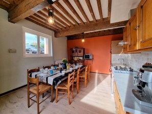 Un comedor con una mesa larga dispuesta para seis, sillas de madera, un mueble de madera, un microondas y una cafetera.