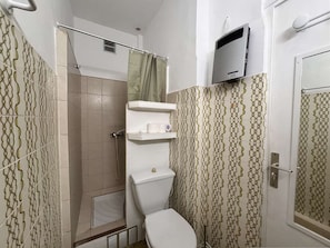 A bathroom with patterned tiles, a toilet, a shower, and a mounted television. - Studio with stunning sea view - 2 guests (Saint-Cyr-sur-Mer)