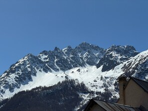 Ein Berg mit schneebedeckten Gipfeln und ein Gebäude mit geneigtem Dach.