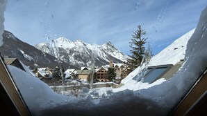 Ett snötäckt berglandskap med utsikt över en byggnad med många fönster och ett väl synligt kyrktorn.