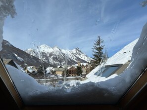 Eine verschneite Berglandschaft mit Blick auf ein Gebäude mit vielen Fenstern und einem sichtbaren Kirchturm.
