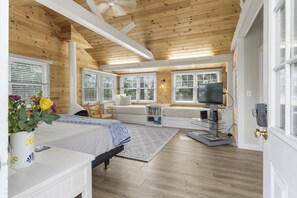 A bedroom with a bed, a window seat, a TV, and a bookshelf. - Amore | Romantic Coastal Cottage Near Spruce Point (Boothbay Harbor)