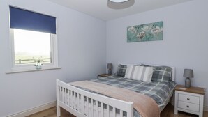 A bedroom with a bed, bedside tables, a window with a view, and a painting on the wall. - Fleetwood (Richmond)