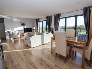 Un salon spacieux comprenant un canapé, un téléviseur et un coin repas avec une table et des chaises.