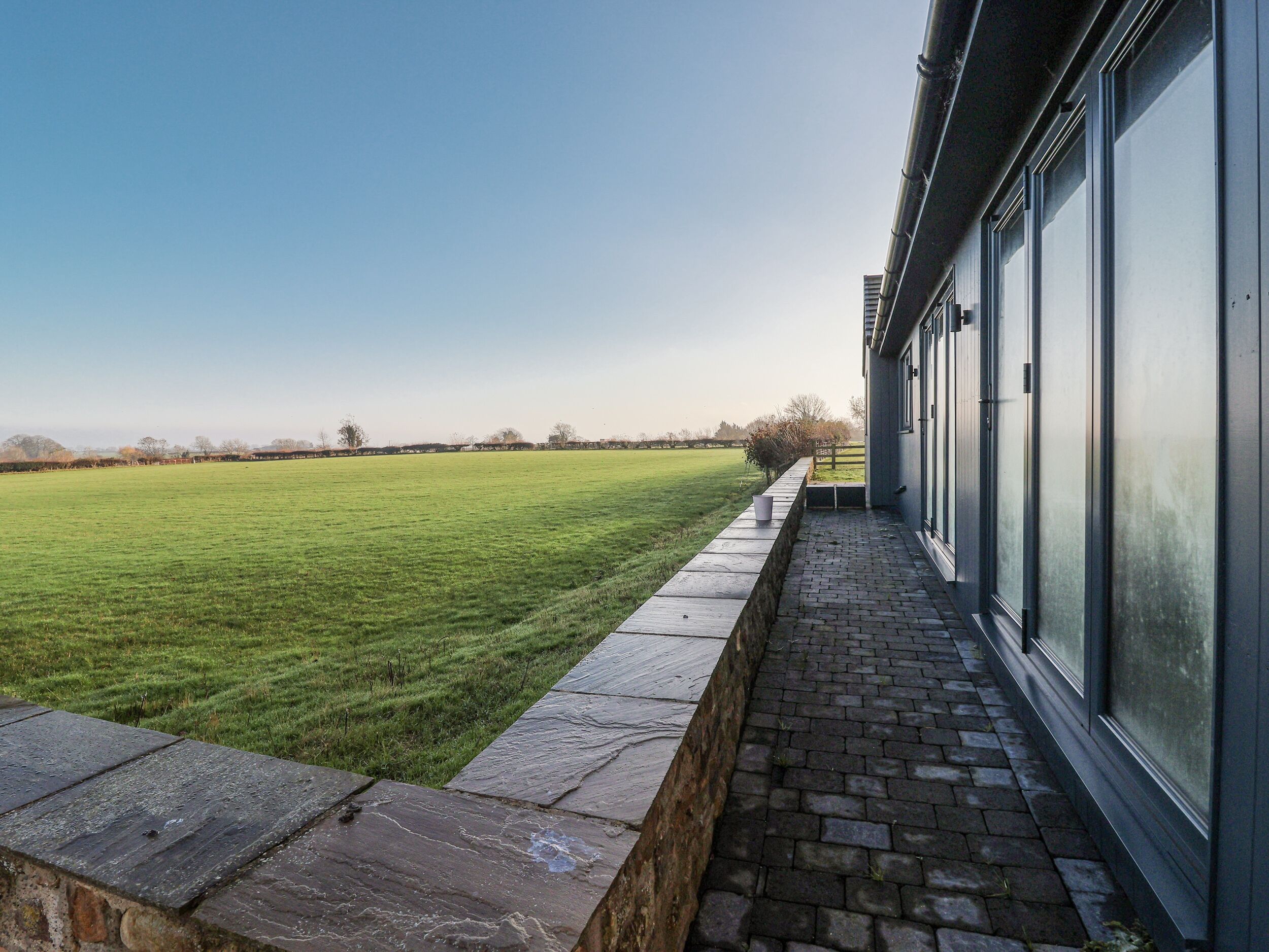 A building with a brick pathway leading to a grassy field.