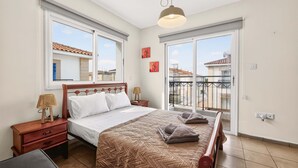 Ein Schlafzimmer mit einem Bett, Nachttischen, einer Lampe und Blick ins Freie.