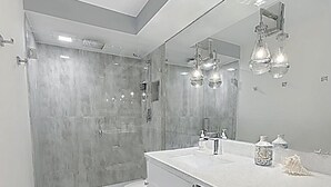 A modern bathroom with a walk-in shower, a toilet, a sink with a mirror, and a dishwasher. -  The Coastal - Gulf View 8th floor condo at Bonita Springs Beach & Tennis Club (Bonita Springs)