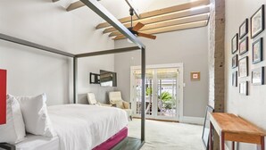 Un dormitorio con cama, una silla, una mesa y un balcón con vistas.