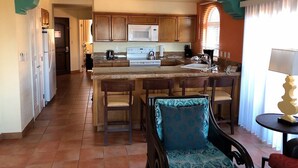 A kitchen with a central island, wooden cabinets, and a dining area with chairs. - Cozy 1-bedroom deluxe condo with AC in lovely San José del Cabo (San José del Cabo)