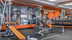 Ein Fitnessraum mit verschiedenen Trainingsgeräten, einer Bank und einem Dumbbell-Gestell.