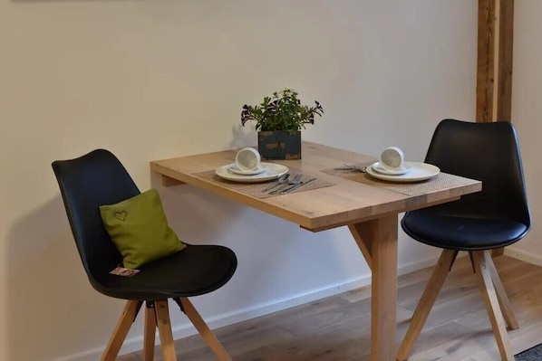 A dining table with two chairs, a potted plant, and a small table setting.