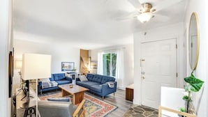 A modern living room with a blue sofa set, a wooden coffee table, and a patterned rug.
