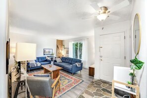 Ein modernes Wohnzimmer mit einem blauen Sofagarnitur, einem Holztisch und einem gemusterten Teppich.