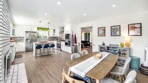 A modern kitchen with a central island, bar stools, and a dining table with chairs.
