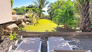 A garden view with a pathway leading to a seating area with two loungers. - Ti Lodge – A Romantic Getaway with Ocean View (Cul-de-Sac)