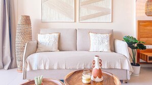 Ein modernes Wohnzimmer mit einer Couch, dekorativen Kissen, einer gewobenen Lampe und einem Couchtisch mit einer Vase und einer Flasche.