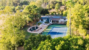 A house with a tennis court, surrounded by lush greenery and palm trees. - Private Estate: House + Cottage, Pool & Tennis (Ojai)