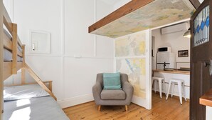 A room with a bed, a chair, a map on the wall, and a kitchen area. - The Pilots Cottage in Apollo Bay (Apollo Bay)