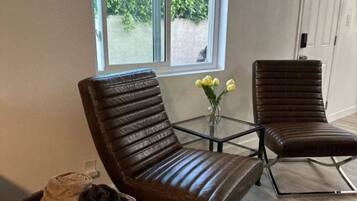 A modern living room with two brown leather chairs, a glass coffee table, and a wicker basket.