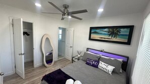 A bedroom with a bed, a ceiling fan, a painting of a beach, and a wardrobe. - Walkable to SoFi, Intuit Dome, Kia Forum World Cup (Lennox)
