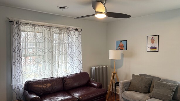 A living room with a brown leather sofa, a grey sofa, a standing floor lamp, and a ceiling fan. - Roomy 2 Bedroom Apartment 20 Minutes from Philadelphia (glenolden)