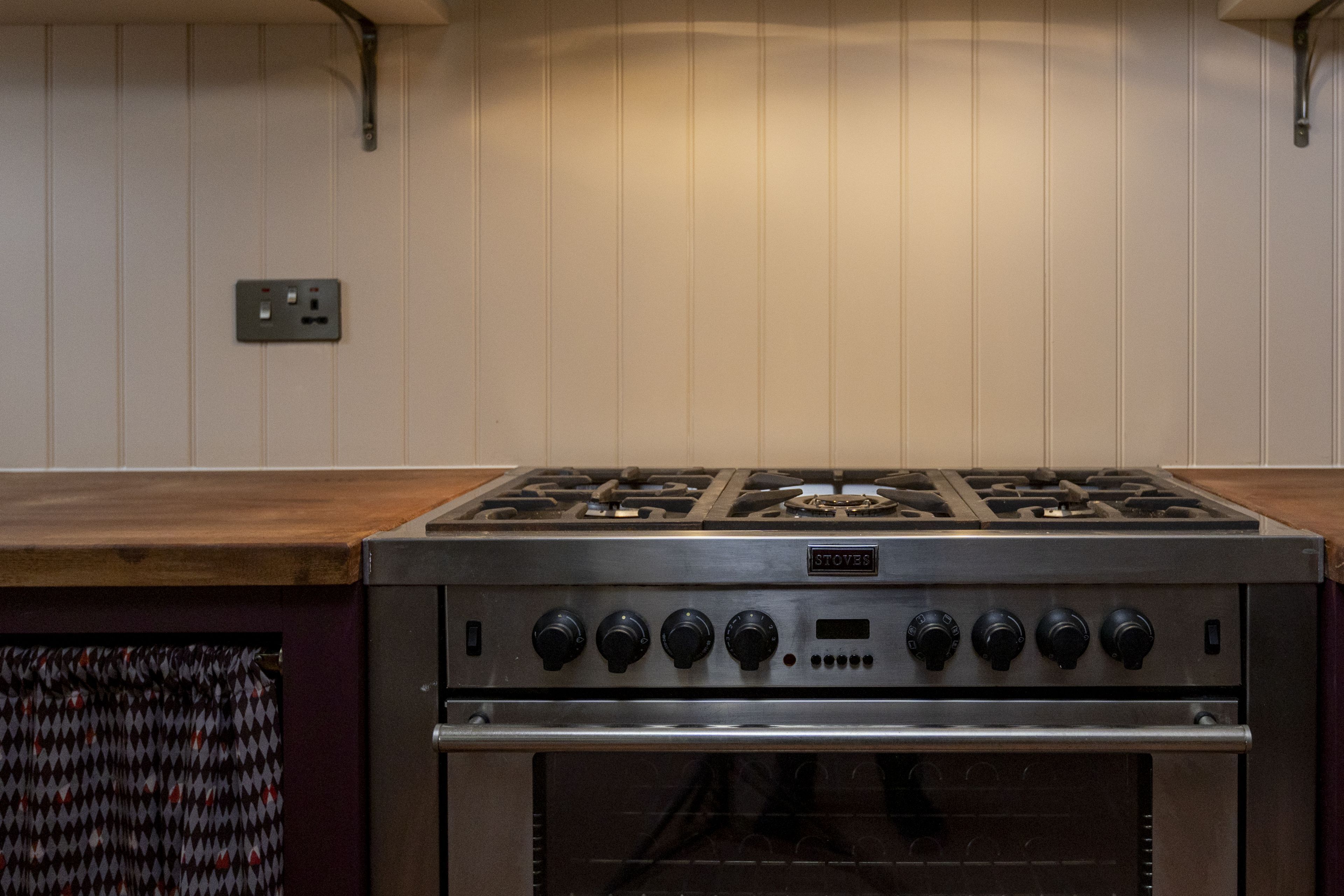 A kitchen with a gas stove, oven, and a wooden countertop.