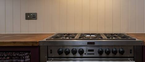 A kitchen with a gas stove, oven, and a wooden countertop.
