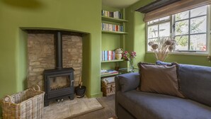 A cozy living room with a stone fireplace, a bookshelf, a sofa, and a window with a view. - Horseshoe Cottage - sleeps 4 guests  in 2 bedrooms (Oxfordshire)