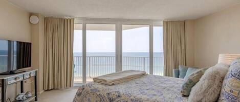 Une chambre d’hôtel avec un grand lit, une télévision et un balcon donnant sur la mer.