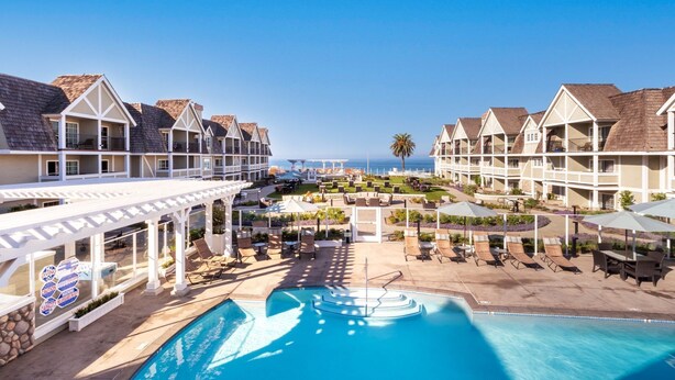 Een resort met meerlaags gebouwen, een centraal gelegen zwembad, buitenzitgedeeltes en uitzicht op de oceaan.