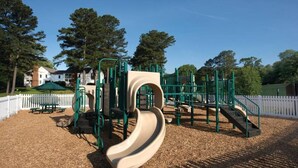 A playground with a slide and climbing structures, surrounded by a white picket fence and trees. - Quaint studio near historic Colonial Williamsburg (Williamsburg)