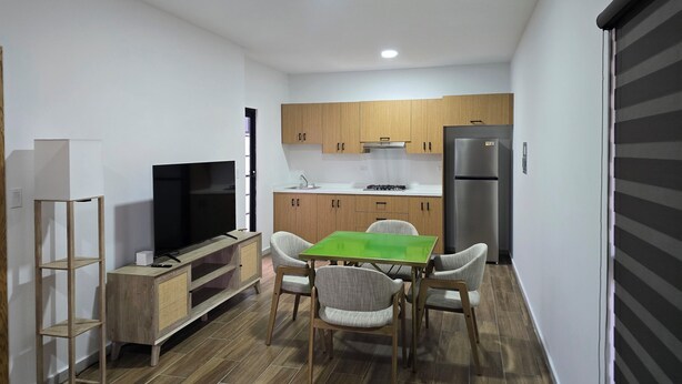 A compact kitchen with wooden cabinets, a built-in stove, and a refrigerator. - New centrally located apartment with shared balcony. (Chihuahua)