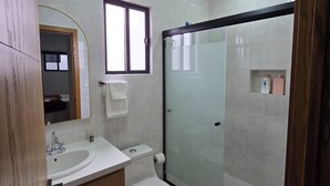 A modern bathroom with a sink, toilet, and glass shower enclosure. - New centrally located apartment with shared balcony. (Chihuahua)