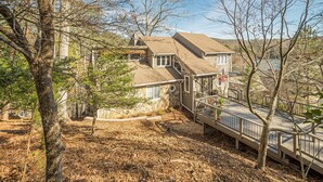 A house with a stone foundation, a wooden deck, and a view of a river. - Lakefront Luxury - Boat Slip - Kayaks - Game Room (Waleska)