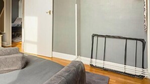 A bedroom with a bed, a radiator, and a door leading to another room.