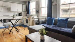 A compact living space with a kitchenette, a dining area, and a sofa with blue cushions.
