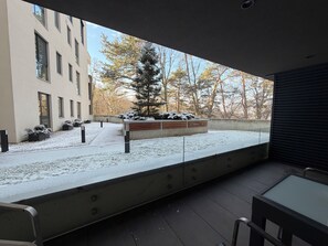A modern building with a snow-covered courtyard, a bench, and a view of trees. - Cozy Forrest-side 2BR - Parking & Patio (Brașov)
