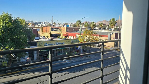 A balcony with a metal railing overlooking a street with buildings and palm trees. - New centrally located apartment with balcony. (Chihuahua)