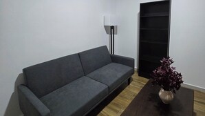 A living room with a grey sofa, a wooden coffee table with a vase, a floor lamp, and a black shelving unit. - New centrally located apartment with balcony. (Chihuahua)