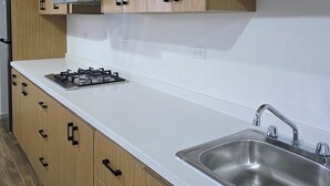 A modern kitchen with wooden cabinets, a white countertop, a stainless steel sink, and a gas stove. - New centrally located apartment with balcony. (Chihuahua)
