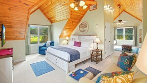 Ein Schlafzimmer mit Bett, Nachttischen, einem Sessel, einer Couch, einem Deckenventilator und einem Fenster.