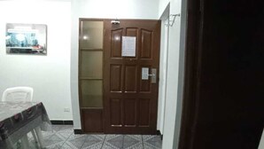 Una habitación con suelo de baldosas estampadas, una puerta de madera con un aviso y una mesa con mantel decorado.