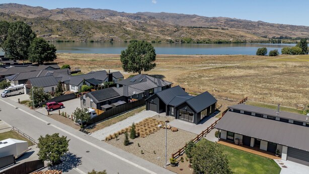 Una zona residencial con casas modernas, una carretera y un lago al fondo.