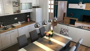 Eine moderne Küche mit weißen Schränken, einer Holzarbeitsplatte und einem Essbereich mit Tisch und Stühlen.
